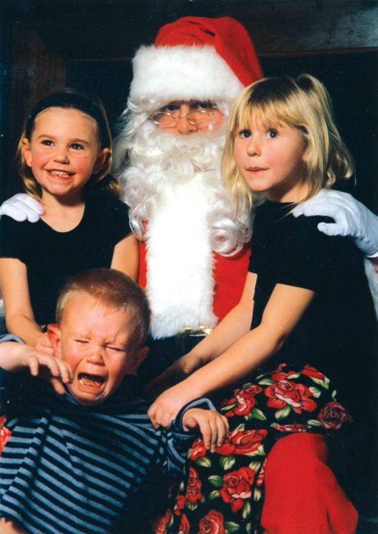 Scared Santa. This is a picture of my grandchildren visiting Cozy Cloud Cottage, December 2000. On your right is Cat Vukelich (5-20-92). On your left is her sister Erin Vukelich (4-29-93). Both girls are trying to restrain their brother Jarrett Vukelich (2-25-97). Sent in by Joan Lescher 708 366-8724.