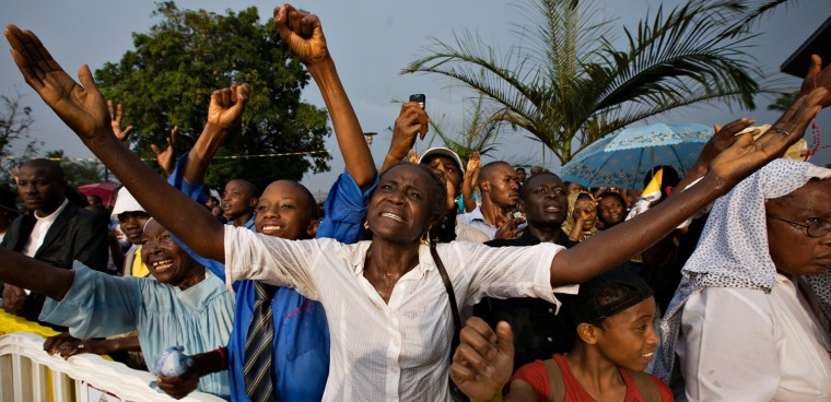Image: Faithful rejoice as the sun bursts through dark thunder clouds during a heavy rain storm moments after Pope Benedict arrived at the basilica to celebrate Vespers in Yaounde