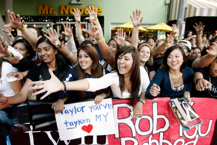 Fans reach for T-shirts that are handed out before the premiere of \"Twilight\" in Los Angeles on Monday, Nov. 17, 2008.  Fans arrived as early as 10:00 a.m. on Sunday to watch stars arrive for the premiere.  (AP Photo/Matt Sayles)