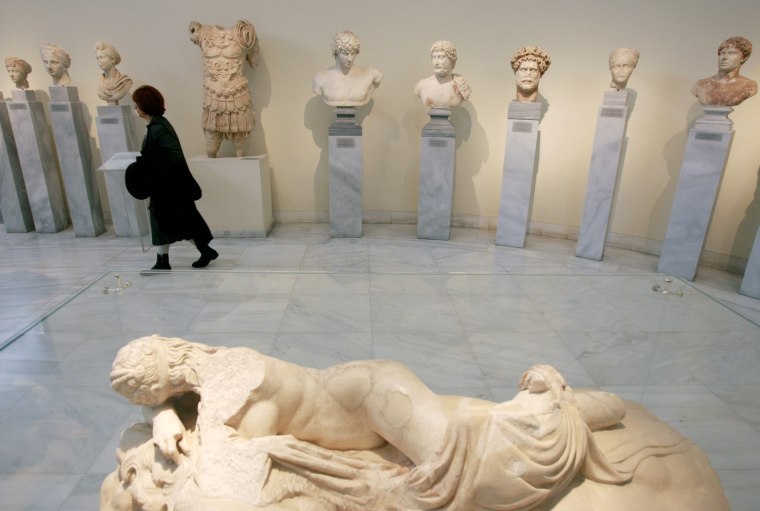 A visitor walks behind the Statue of sleeping Maenad at the Greek National Archaeological Museum in Athens