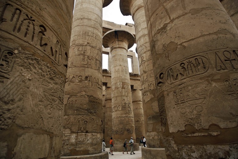 Tourists explore stone columns decorated
