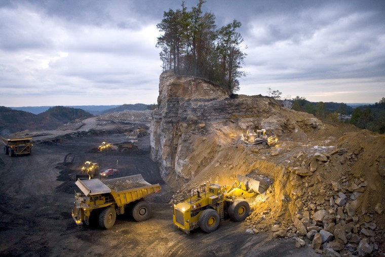 Overburden from blasting is removed by various machines.
Mining operations work around the clock at amazing speed; this lonely stand of trees disappeared in barely a day. The small bulldozer on the upper level pushes loose material down to the loader, which scoops it up into the next earth mover in line which will dump it into a nearby Òvalley fill,Ó burying the stream there.