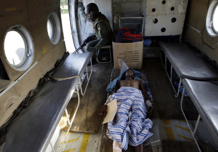 A Sri Lankan government soldier lies injured on a stretcher as another mans a machine-gun in a helicopter lifting off from the town of Kilinochchi located near the 'No Fire Zone' in northern Sri Lanka