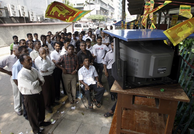 Image: Sri Lankans gather around a television set on a street as they watch an address to the nation from Parliament by President Rajapaksa in central Colombo