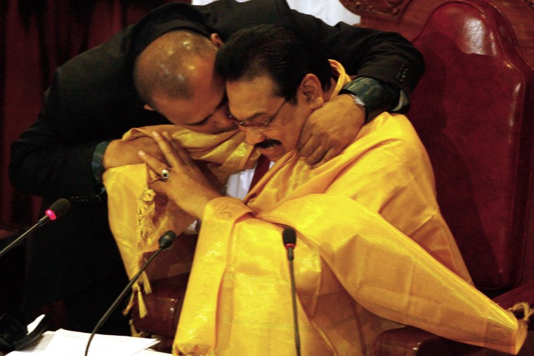 Image: Sri Lankan President Rajapaksa has a garment put around him by Minister of Water Supply and Drainage Athaullah after addressing the nation in the parliament in Colombo