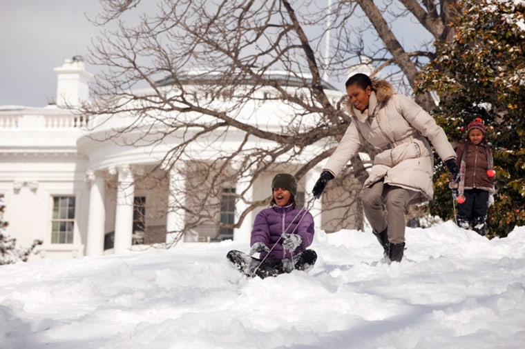 First Lady Michelle Obama with daughters Malia and Sasha sled in the snow on the South Lawn of the White House 3/2/09. 
Official White House Photo by Pete Souza