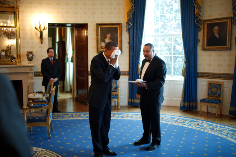 President Barack Obama wipes his face with a cloth handed to him by  White House Butler Von Everett in the Blue Room following an event with business leaders in the East Room 1/28/08
Official White House Photo by Pete Souza