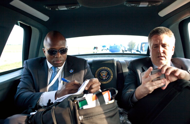 President Barack Obama's personal aide Reggie Love, left,  and White House physician Dr. Jeffrey Kuhlman check their notes as they travel in the Presidential motorcade April 4, 2009 in Strasbourg, France. White House Photo/Pete Souza