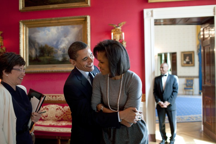 President Barack Obama hugs First Lady Michelle Obama  in the Red Room while Senior Advisor Valerie Jarrett smiles prior to the National Newspaper Publishers Association (NNPA) reception 3/20/09.
 Official White House Photo by Pete Souza