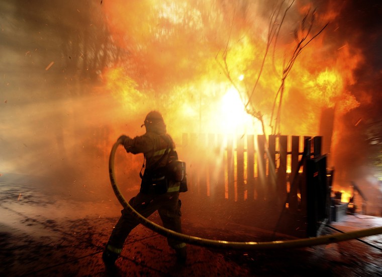A firefighter sprays water on a house burning during the Jesusita fire in Santa Barbara