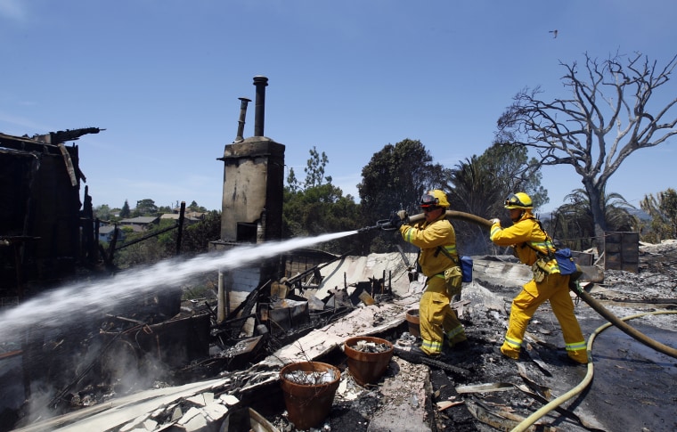 Image: Firefighters spray water on the rubble of a house that burned during the Jesusita fire in Santa Barbara