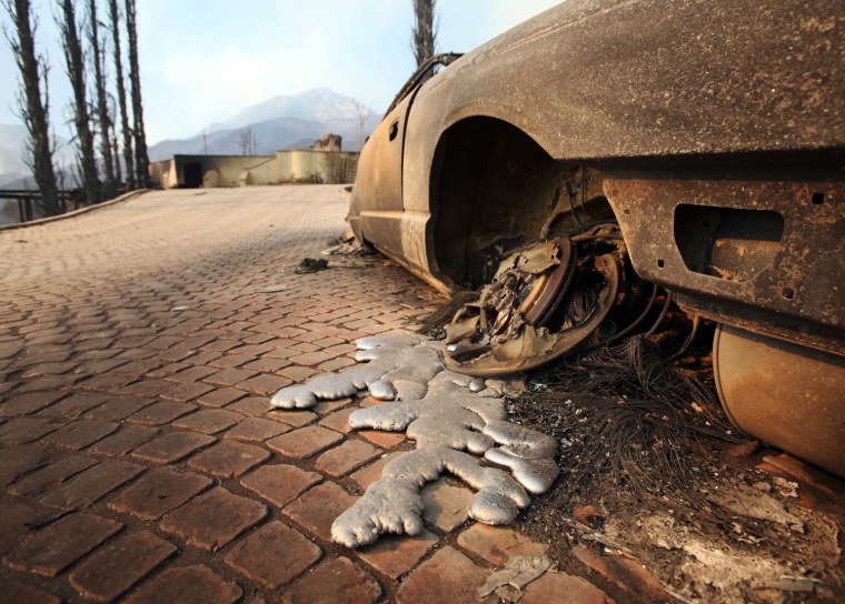 Molten aluminum has flowed from the wheels of a burned-out car, in front of a home destroyed after the Jesusita fire swept through Santa Barbara, Calif., Thursday, May 7, 2009.  (AP Photo/Reed Saxon)
