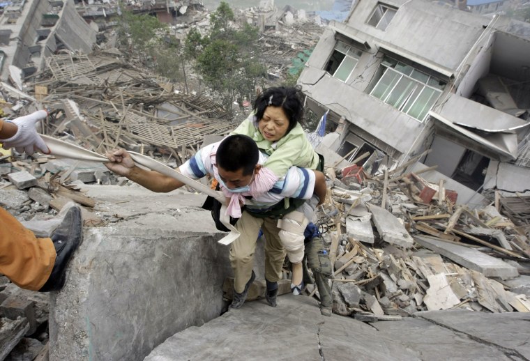 A rescue worker carries a survivor from a collapsed building in the old city district near a mountain at the earthquake-hit Beichuan county