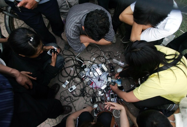 Residents charge their mobile phones after a generator was brought to a temporary outdoor shelter in Dujiangyan, in China's southwest Sichuan province Wednesday May 14, 2008. Thousands of residents are sleeping under makeshift shelters after a major earthquake Monday destroyed houses in the city. Many others are afraid to return to their homes. The official death toll from Monday's earthquake reached almost 15,000 Wednesday, with many thousands more missing. (AP Photo/Greg Baker)