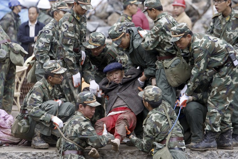 Soldiers carry a wounded elderly man out from a collapsed building at the earthquake-hit Beichuan County