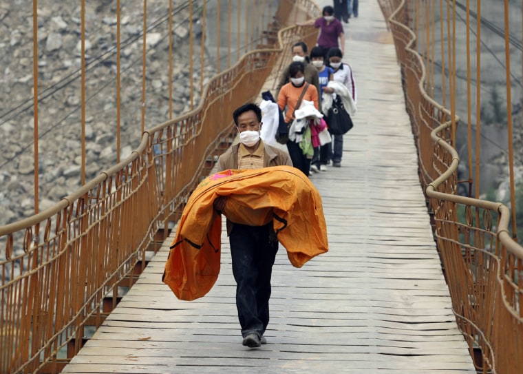 The body of a girl who was found in the rubble of the Qushan kindergarten is carried across a bridge in Beichuan county