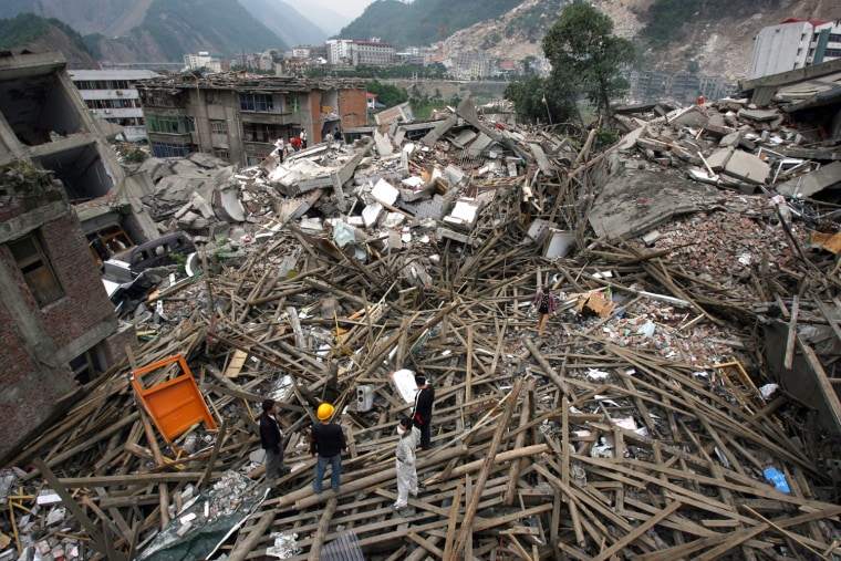 Rescuers gather on a collapsed building in the earthquake-struck county of Beichuan, southwest China's Sichuan province on May 15, 2008. China said that over 50,000 people had likely died in the devastating earthquake that hit its southwest as time runs out to save survivors buried in the rubble.    CHINA OUT GETTY OUT    AFP PHOTO (Photo credit should read STR/AFP/Getty Images)