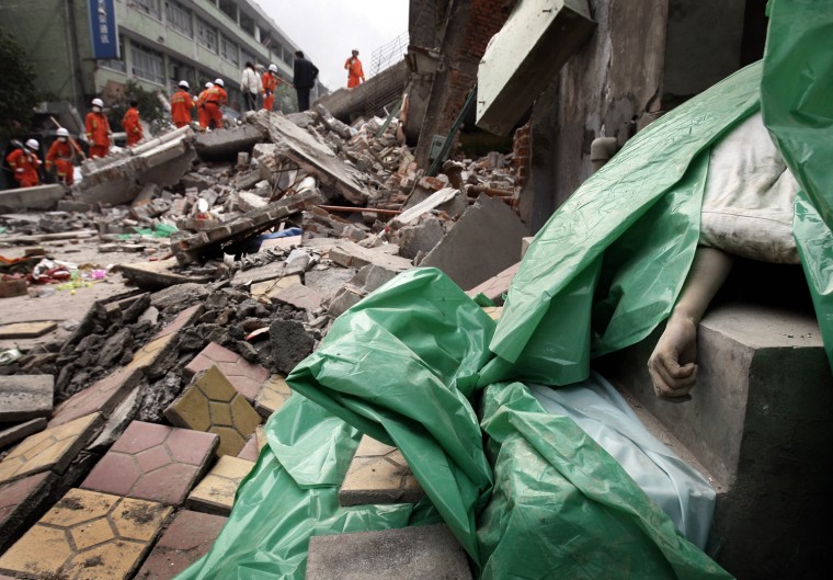 A victim's hand is seen on the right covered with blanket while rescue team members search for survivor following the powerful earthquake in Beichuan county, Southwestern of Sichuan province, China, Friday, May 16, 2008. (AP Photo/Andy Wong)