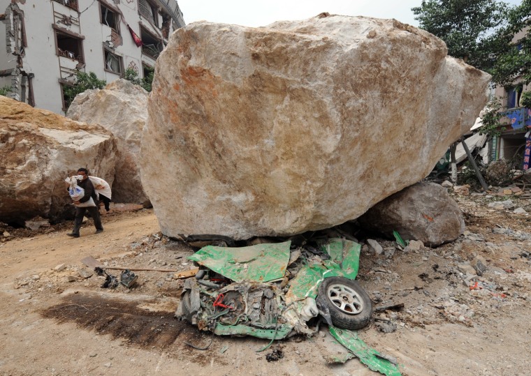 A flattened taxi lies under one of the boulders that crushed it on the earthquake damaged streets of Beichuan in Sichuan Province on May 16, 2008.  Beichuan is one of the areas hit hardest by the quake, which has caused deaths across at least four provinces and regions. At least 1,000 Beichuan students and teachers were killed or buried in the collapse of the town's secondary school and up to 5,000 people in the area may have also been killed by the 7.8-magnitude quake       AFP PHOTO/Mark RALSTON (Photo credit should read MARK RALSTON/AFP/Getty Images)