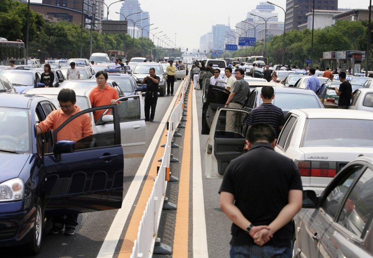 Beijing motorists on the six-lane Jianguomenwai Avenue stand beside their cars honking their horns for three minutes to honor the victims of last week's devastating earthquake, Monday, May 19, 2008. Across the country traffic stopped and people stood in silence at 2:28 PM, the one-week anniversary of the quake. (AP Photo/Robert F. Bukaty)