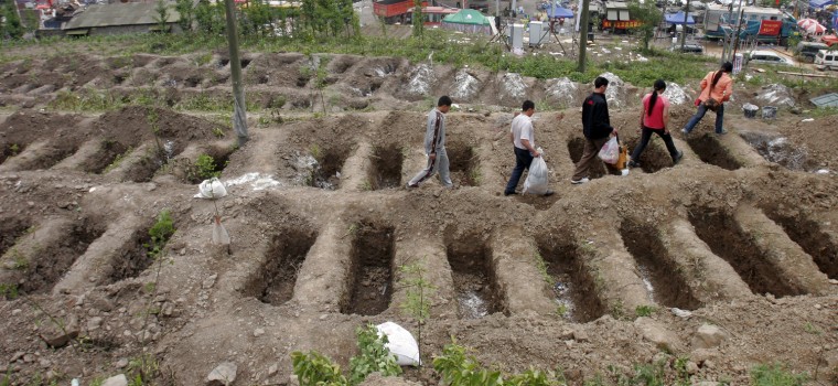 People walk past empty graves at a burial site in earthquake-hit Hongbai town