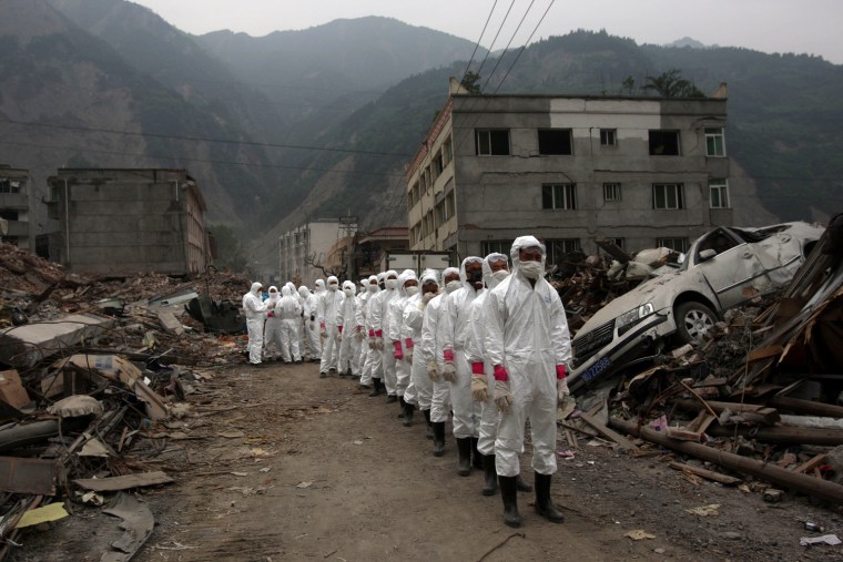 Chinese rescue workers line up to leave the area for they safety as authorities prepare to destroy earthquake damaged buildings using explosives and construction equipment in Yingxiu in Wenchuan County of southwest China's Sichuan province Tuesday, May 27, 2008. The number of deaths from the quake has climbed further toward an expected toll of 80,000 or more. The Cabinet said Tuesday that 67,183 people were confirmed killed _ up by about 2,000 from a day earlier _ and 20,790 were sill missing.  (AP Photo/David Guttenfelder)