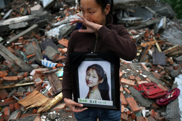 A mother cries as she holds a photo of his daughter who was killed in an earthquake, as she stands in the ruins of the Fuxin No.2 Primary School in Wufu, in China's southwest Sichuan province Thursday May 29, 2008. China's central govenment has promised to punish harshly anyone found responsible for poor constuction of schools, though it has also said that building codes in the stricken region did not require structure to be able to withstand a quake of the power of the magnitude 7.9 earthquake on May 12. (AP Photo/David Guttenfelder)