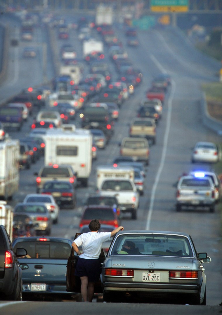 A woman stands outside her car on Interstate-45 near downtown Houston on Thursday, Sept. 22, 2005. Thousands of people fleeing hurricane Rita and are evacuating the Texas coast and officials will be reversing the Southbound lane on the interstate to four lanes of north bound flow.  (AP Photo/Rick Bowmer)