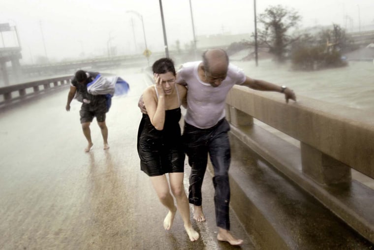 Jennifer Cooper, 33, (black dress),  Otis Brown, 67, (holding Jennifer Cooper, white T-Shirt) and Alber Jean, 50, fight their way through the wind driven rain of Hurricane Katrina and up an Interstate 610 off-ramp after escaping the roof level flood waters in the Clermont Driver area of New Orleans Monday morning.  The three were part of a larger group who had escaped the flood waters by taking an aluminum motor boat to the off-ramp.