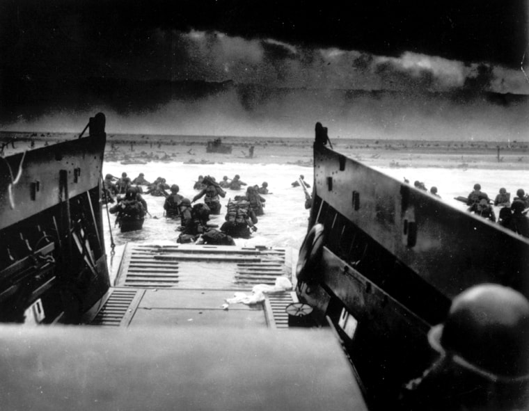 While under attack of heavy machine gun fire from the German coastal defense forces, these American soldiers wade ashore off the ramp of a U.S. Coast Guard landing craft on June 6, 1944, during the Allied landing operations at the Normandy. (AP Photo)
