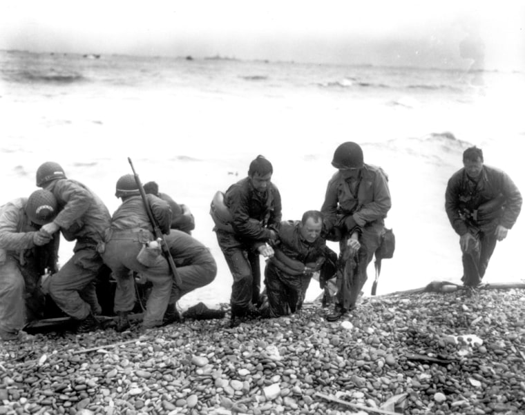 Members of an American landing unit help their exhausted comrades ashore during the Normandy invasion, on June 6, 1944. The men reached the zone code-named Utah Beach, near Sainte-Mere-Eglise, on a life raft, after their landing craft was hit and sunk by German coastal defenses.  (AP Photo)