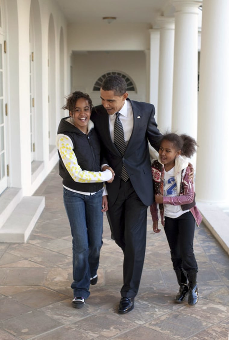 President Barack Obama walks down the White House Colonnade with his arms around daughters  Malia and Sasha in this handout photo taken in Washington