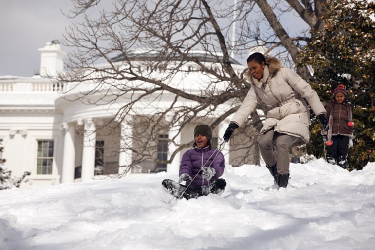 First Lady Michelle Obama sleds with daughters Malia and Sasha in the snow on the South Lawn of the White House in this handout photo taken in Washington