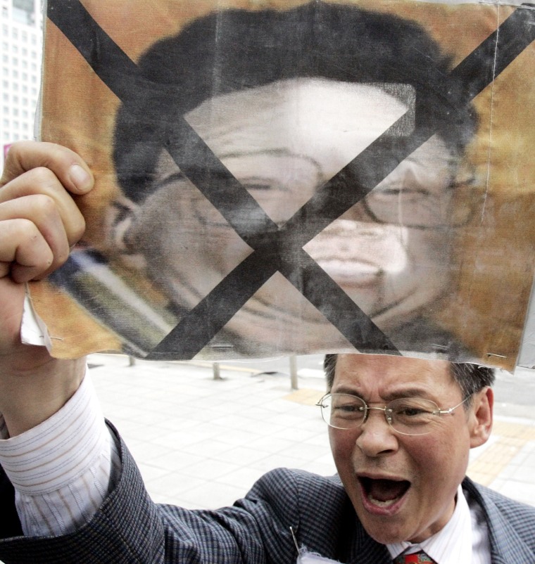 A South Korean protester holds a picture of North Korean leader Kim Jong Il marked with a cross, denouncing the North's test-firing of seven missiles in Seoul, Friday, July 7, 2006. South Korea said Friday that it had turned down a North Korean proposal to hold military talks this week, citing tension over the North's test-firing of seven missiles.  (AP Photo/ Lee Jin-man)