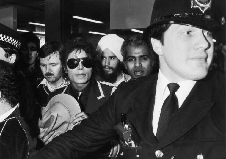 Michael Jackson is lead through a crowd by policeman