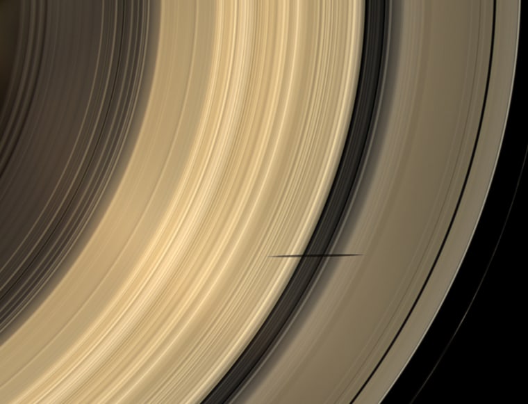 The shadow of Saturn's moon Mimas dips onto the planet's rings and straddles the Cassini Division in this natural color image taken as Saturn approaches its August 2009 equinox.

The novel illumination geometry created as the Saturnian system approaches equinox allows moons orbiting in or near the plane of Saturn's equatorial rings to cast shadows onto the rings. These scenes are possible only during the few months before and after Saturn's equinox which occurs only once in about 15 Earth years. To see a movie of Mimas' shadow moving across the rings, see PIA11658 <view.php?id=5591>. Mimas (396 kilometers, 246 miles across) does not appear in this image, but the moon has a flattened, or oblate, shape (see PIA07534 <view.php?id=1138>).

This view looks toward the sunlit side of the rings from about 52 degrees below the ringplane. Images taken using red, green and blue spectral filters were combined to create this natural color view. The images were obtained with the Cassini spacecraft wide-angle came