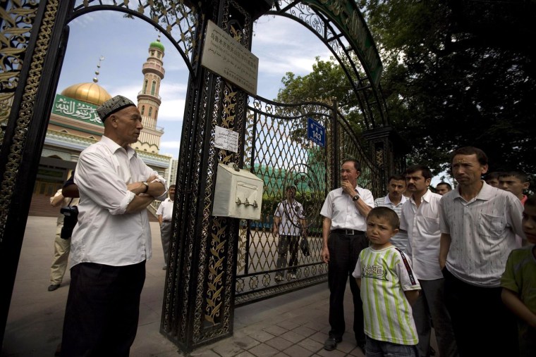 Image: Ethnic Uygurs stand outside a closed mosque minutes before Friday prayer in Urumqi, China