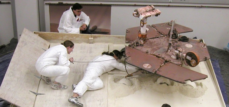 After a Crabwalk Test

Mars Exploration Rover team members prepare a testing setup for a subsequent experiment after an experiment driving the rover in a crablike motion, with all four corner wheels angled to the right. Clockwise from top: Scott Maxwell, Pauline Hwang, Kim Lichtenberg. 

This work on July 9, 2009, was part of a series of tests at NASA's Jet Propulsion Laboratory, Pasadena, Calif., designed to determine the best way to get NASA's Spirit rover out of a Martian patch of soft soil called \"Troy,\" where Spirit's wheels have dug in. The test setup, in a box that team members are calling the dustbin, simulates the situation at Troy. The box holds about 2.7 tons of a powdery mixture of diatomaceous earth and fire clay. This material has physical properties similar to the soil at Troy. The top surface is sloped at 10 degrees.