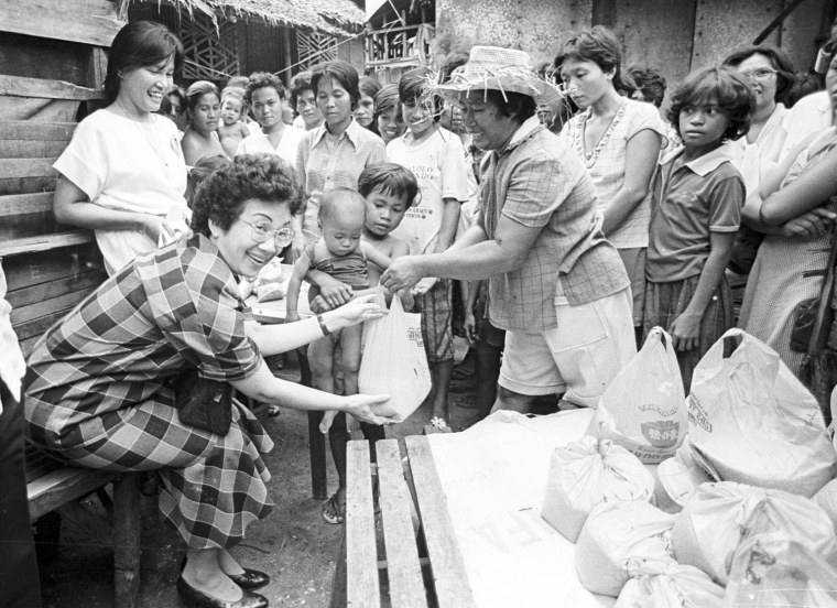Image: File picture shows Aquino distributing food and sugar to workers during her visit to the families of some 20 peasants and bus drivers killed by military gunfire in Escalante town