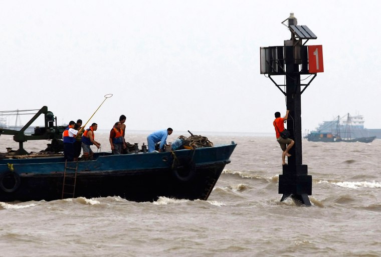 Image: Rescuers try to get hold of a man who is stranded by floods as Typhoon Morakot approaches in Shanghai