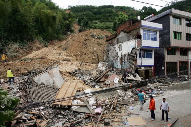 Image: Residents look at debris after a landslide