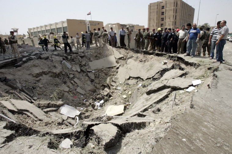Image: Residents and security personnel gather around a crater after a bomb attack outside the Iraqi Ministry of Foreign Affairs in Baghdad