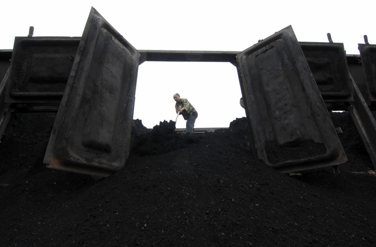 Image: A worker unloads coal from a freight train in Xiangfan