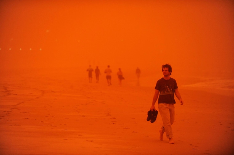 Image: Beachgoers walk through the haze created by a dust storm at Bondi Beach in Sydney