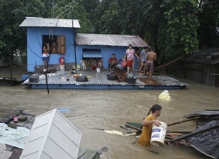 Image: Residents wait to be evacuated from a partially submerged house during flooding in Bocaue