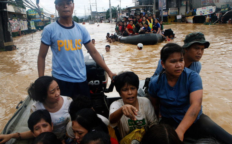 Image: Residents are evacuated by police on rubber boats during flooding in Cainta Rizal