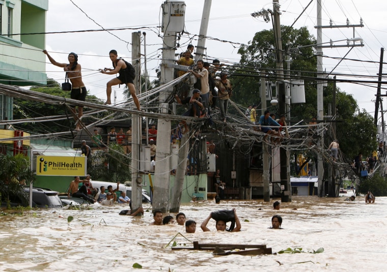 Image: Residents stand on electric wires to stay on high ground while others wade in neck-deep flood waters caused by Typhoon Ondoy in Cainta Rizal