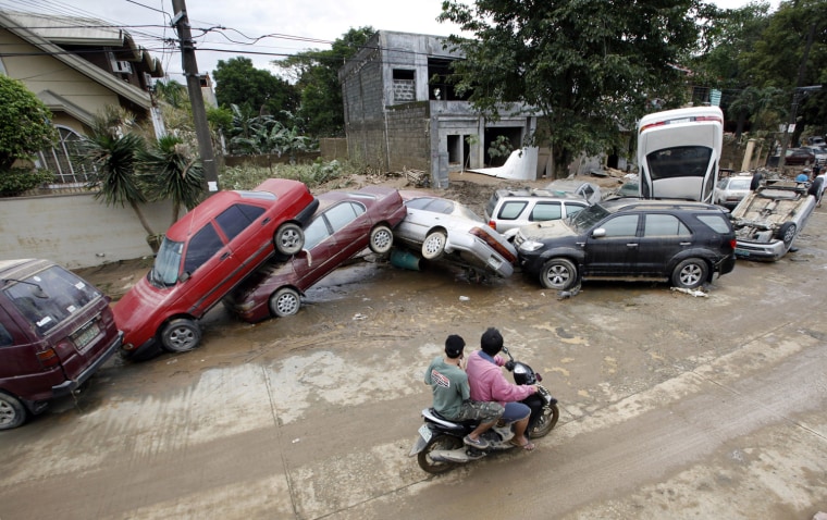 Image: Motorists drive by vehicles lined up along a road after flash floods caused by Typhoon Ondoy hit Provident Village in Marikina City, Metro Manila