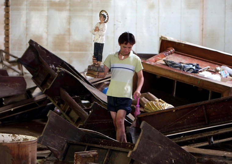 Image: A Filipino carries a Catholic statue from inside a damaged church in Marikina City