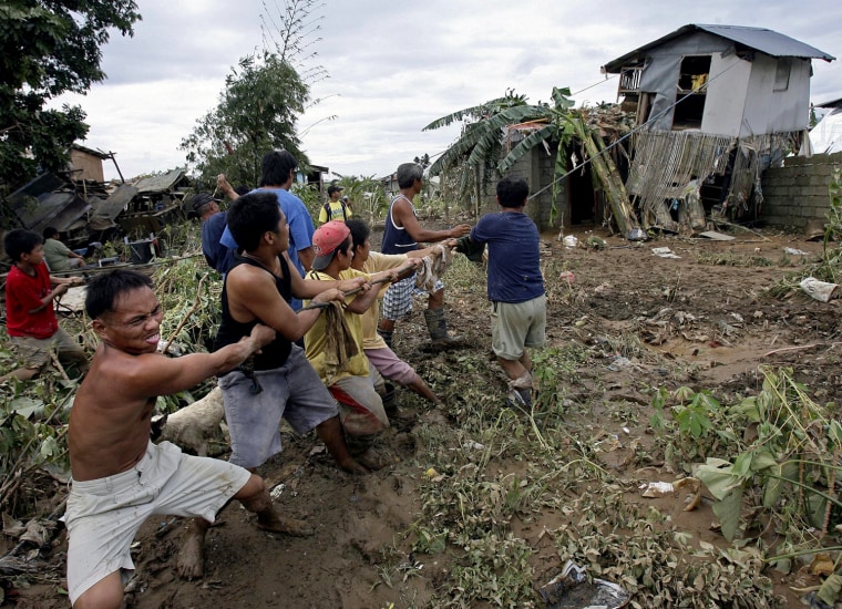 Image: Filipinos help each other in pulling a house that was uprooted by floods caused by Typhoon Ketsana